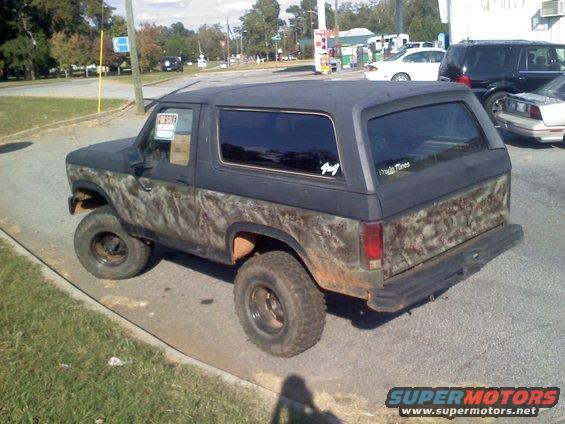 Ford Bronco with custom camouflage paint and lifted suspension. "FOR SALE" sign in window