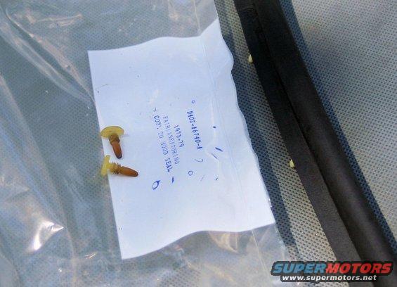 Two plastic fasteners and a document with part numbers and dates