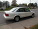 1995 Audi A6 - A white 1995 Audi A6 sedan is parked curbside on a street with houses in the background.