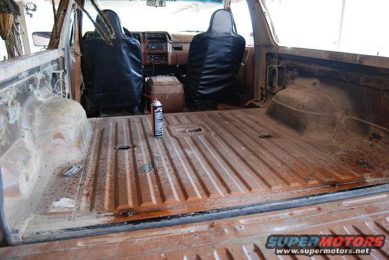 Interior of a rusty orange SUV with black seat covers, showing the cargo area and dashboard