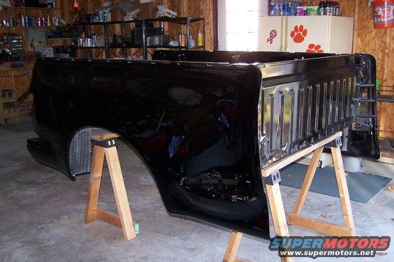 Black truck bed on sawhorses, showing a ribbed tailgate section and wheel well