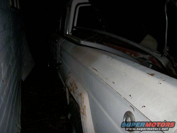 old white pickup truck parked in a narrow space, hood is open