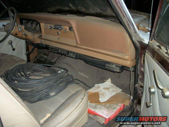 1976 Jeep J-10 interior showing tan dashboard, beige seats, and coiled black cables on the passenger seat