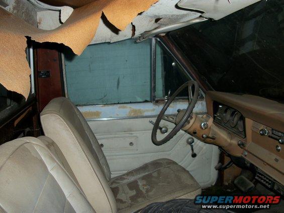 Interior of a 1976 Jeep J-10 with torn headliner and worn seats