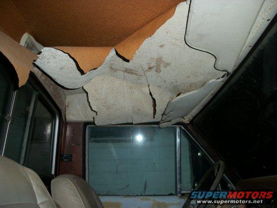 Interior view of a vehicle's headliner peeling away, revealing insulation