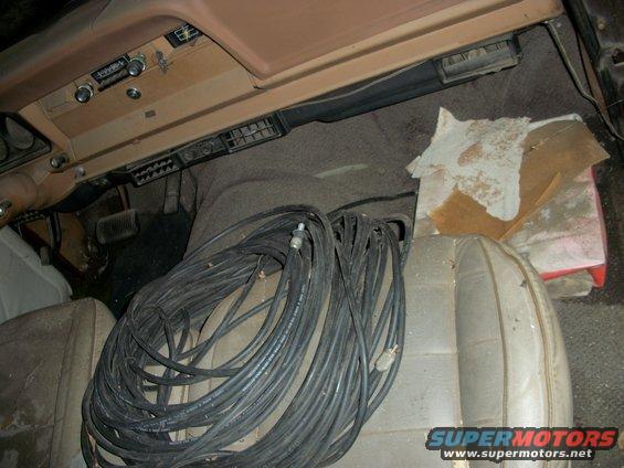 Interior shot of a dusty vehicle, showing dashboard, seats, and a large coil of black cable on the passenger seat