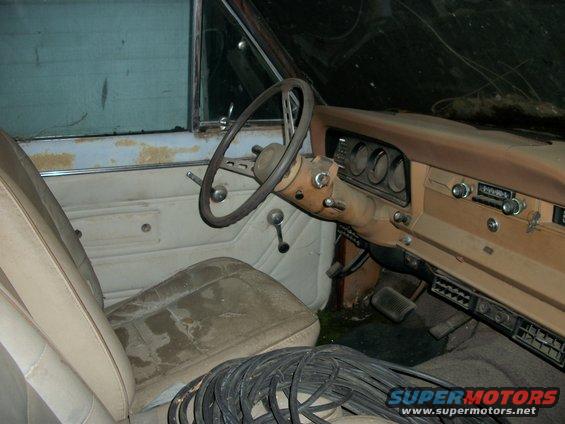 1976 Jeep J-10 interior, dusty tan dashboard, cracked steering wheel, worn seats, and a Supermotors watermark