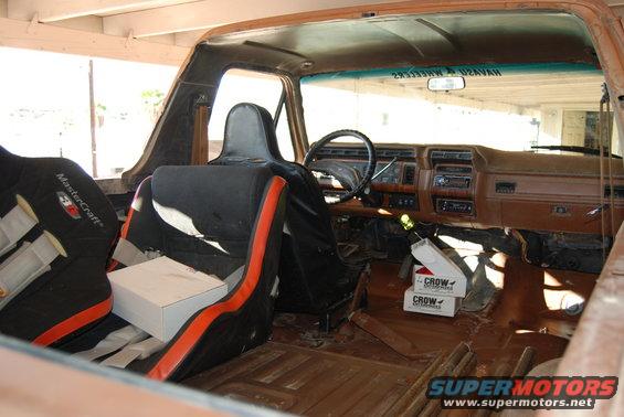 Interior of a brown 1980s Ford Bronco with racing seats, dashboard, and steering wheel visible