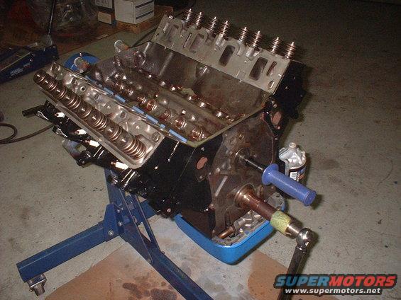 Engine block on a blue stand, showing valve train and crankshaft snout