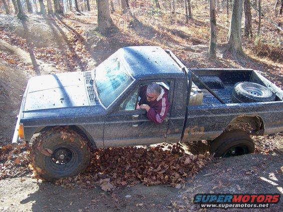 Jeep Comanche pickup truck stuck in mud with driver looking down