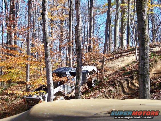 Off-road vehicle navigating a steep, wooded trail during autumn