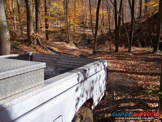 White 1987 Ford F-250 pickup truck bed with a diamond plate toolbox, seen from the rear right