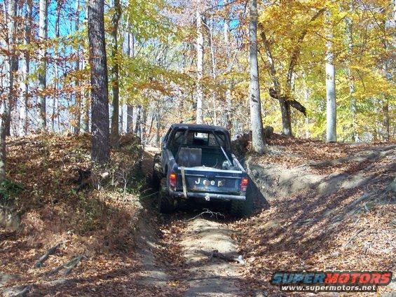 Jeep pickup truck on a dirt trail in autumn woods