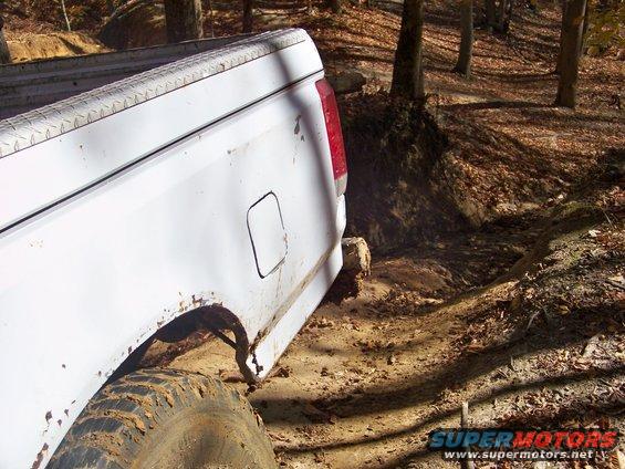 White pickup truck on a muddy trail in the woods