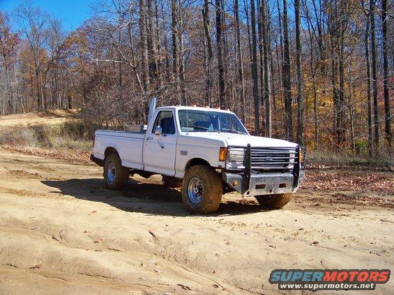 White 1987 Ford F-250 pickup truck with tall exhaust pipe on a dirt road