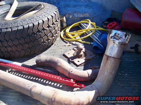 Spare tire, exhaust pipes, tow hitch, and yellow hose in a truck bed