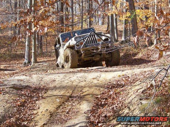 Off-road vehicle stuck in mud on a wooded trail