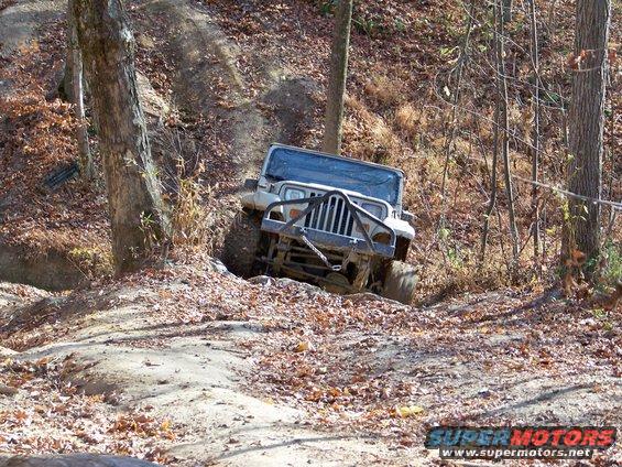 White Jeep Wrangler TJ off-roading on a dirt trail