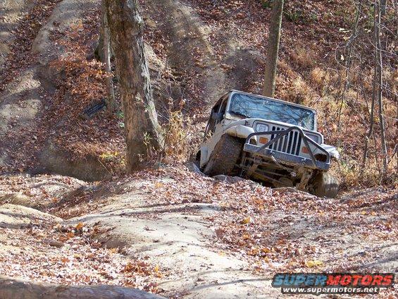 Jeep Wrangler tilted on a muddy, leaf-covered hill during an off-road trip