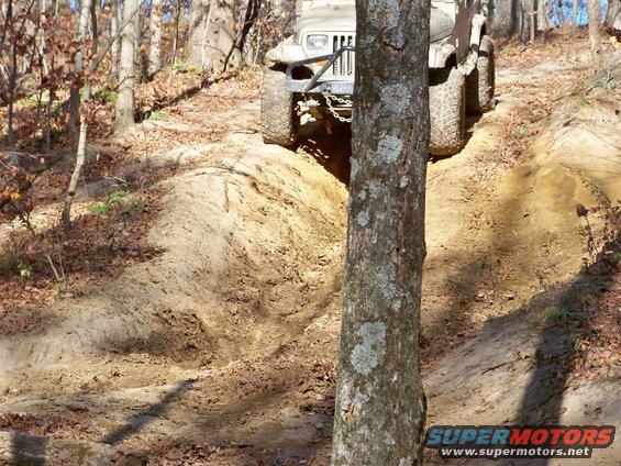 Off-road vehicle climbing a dirt hill, front bumper visible