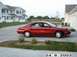 1998 Mercury Sable - A red 1998 Mercury Sable sedan is parked in a driveway next to a residential building.