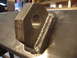 1989 Ford Bronco - A metal bracket with a hole is securely welded to a flat metal plate, showing industrial fabrication.