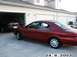 1998 Mercury Sable - A red 1998 Mercury Sable is parked in front of a garage, with another dark-colored car visible inside.