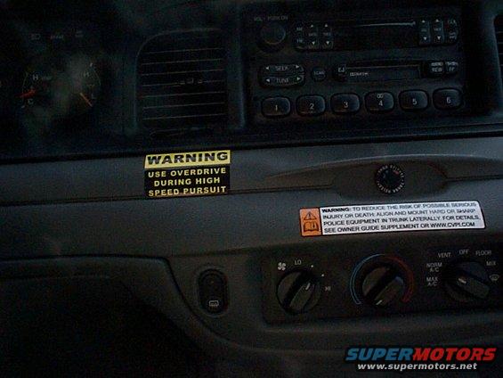 Car dashboard with two warning stickers, climate controls, and radio