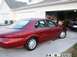 1998 Mercury Sable - Side view of a red 1998 Mercury Sable parked in front of a residential garage, with another vehicle inside.
