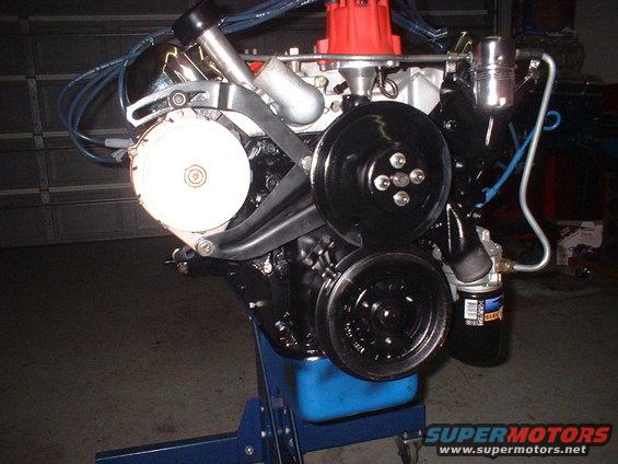 Engine assembly on a blue stand, showing alternator, pulleys, and oil filter