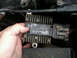 1996 Ford Bronco - A hand holds a Motorcraft voltage regulator, part number F1SF-12A297-CM, showing its ribbed casing and electrical connector.