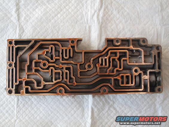 Metal valve body with complex internal channels, showing some rust