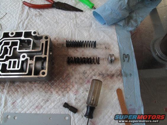 Transmission valve body disassembled with springs, a roller, and a screwdriver on a towel