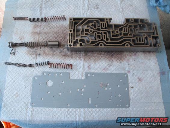 Transmission valve body disassembled with springs and a plunger on a paper towel
