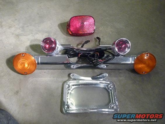 Motorcycle tail light assembly with two amber turn signals and one red brake light, plus a chrome license plate frame