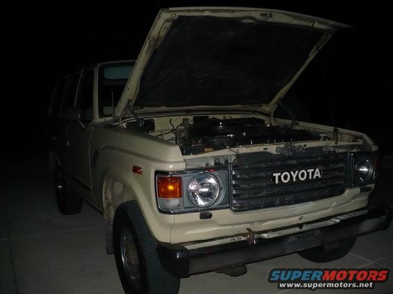 Tan Toyota Land Cruiser with hood open, showing engine. Front view