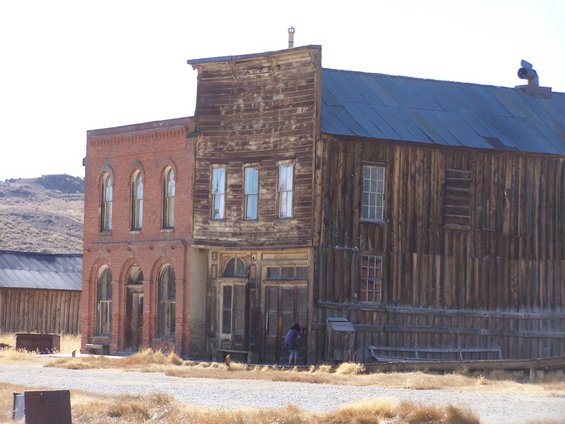 Old brick and wood buildings in a ghost town setting with dry grass in the foreground