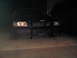 2003 Ford Crown Victoria - A black Ford Crown Victoria Police Interceptor is parked on a concrete surface at night, its headlights illuminated.