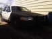 2003 Ford Crown Victoria - This 2003 Ford Crown Victoria police car, seen from a 3q-front angle, features a two-tone black and white paint scheme and a push bar.