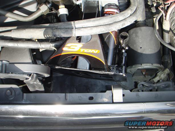 Engine bay with a black and yellow "3 TON" bracket, hoses, and wiring