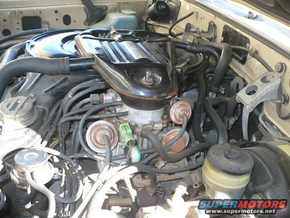 Engine bay with carburetor and hoses, beige exterior paint visible