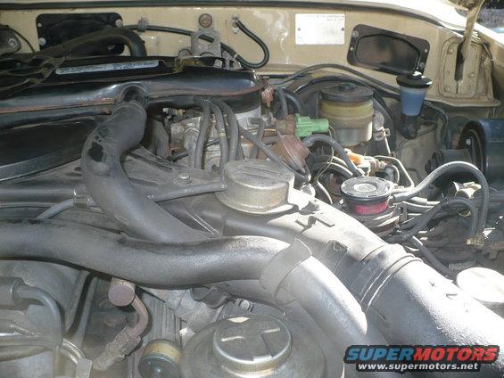 Engine bay of a 1986 Toyota Land Cruiser, showing the engine and various hoses