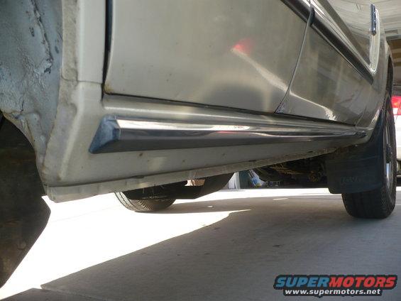 Side view of a vehicle's lower body, showing the running board and wheel well