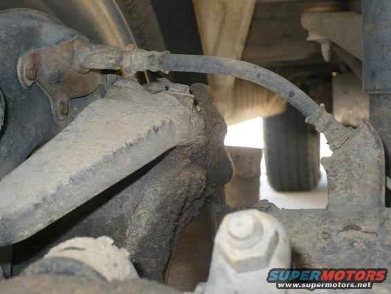 Close-up of rusty brake line and suspension parts on a vehicle