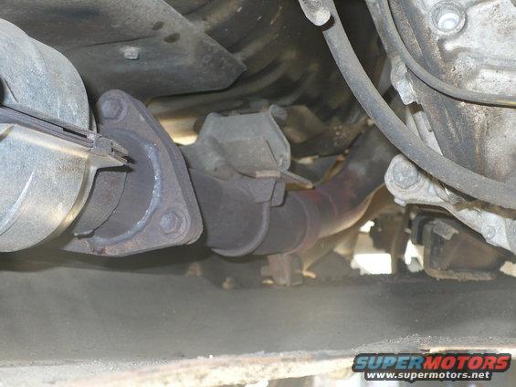 close-up of exhaust pipe and flange connection under a vehicle