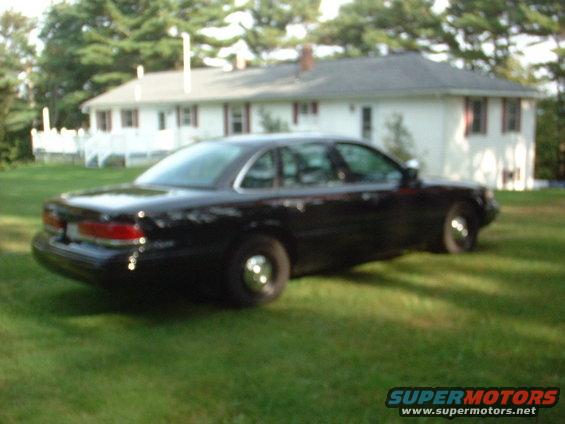 Black 1996 Ford Crown Victoria parked on grass in front of a white house