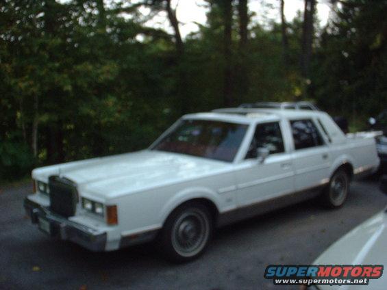 White 1989 Lincoln Town Car parked outside with trees in background