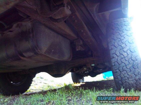 Undercarriage view showing fuel tank, suspension components, and tire tread