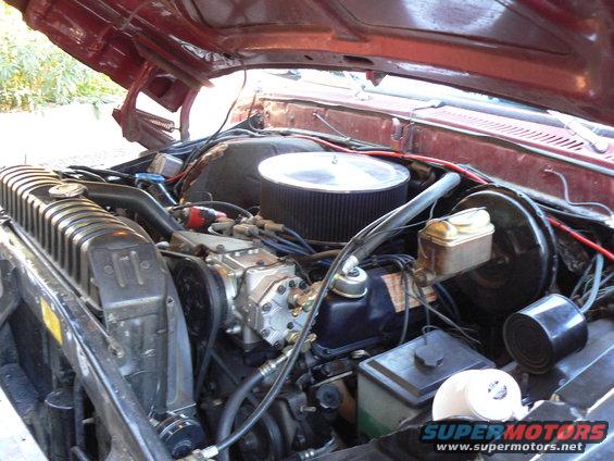 Engine bay of a red Ford truck, showing the V8 engine, radiator, and air filter