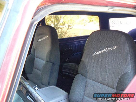 Seats in a vehicle with 'Lightning' embroidered on them. Red exterior visible